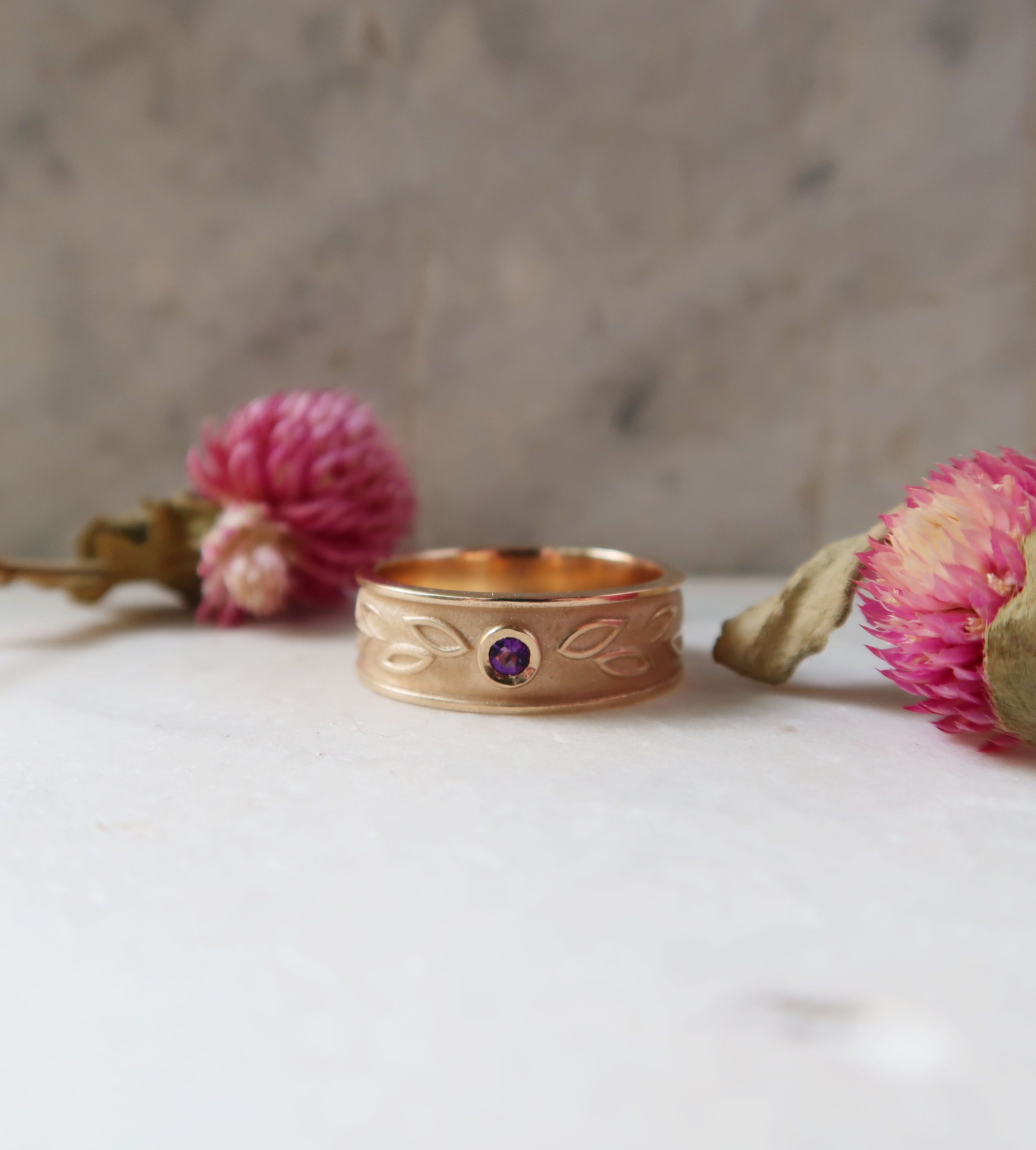 Custom 14k yellow gold and amethyst laurel-inspired wedding band. This ring features both a high-polished finish on the leaves and a sandblasted finish in the recessed areas, adding dimension to this one-of-a-kind wedding band. 