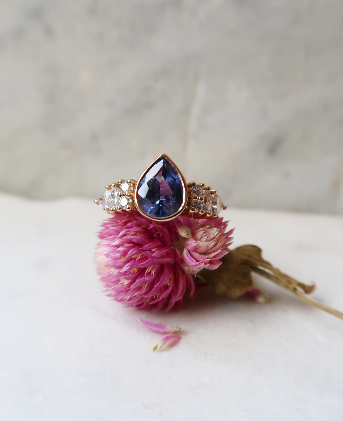 A stunning cornflower blue, pear cut sapphire sits at the heart of this epic custom engagement ring. The centre stone is accented by a mix of shimmering diamonds, in different shapes and sizes, all carefully picked out by my client. 