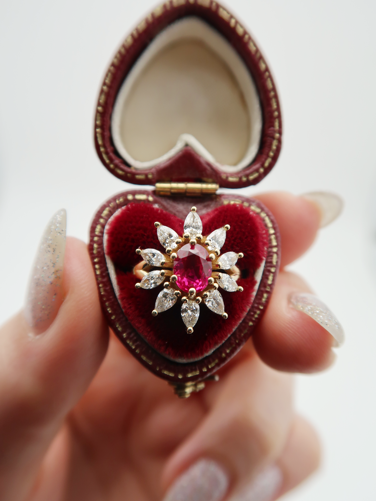 Vintage-inspired 14k yellow gold, natural ruby and diamond engagement ring. The halo of this ring is made from a combination of marquise and pear cut diamonds, adding to the subtle floral motif.