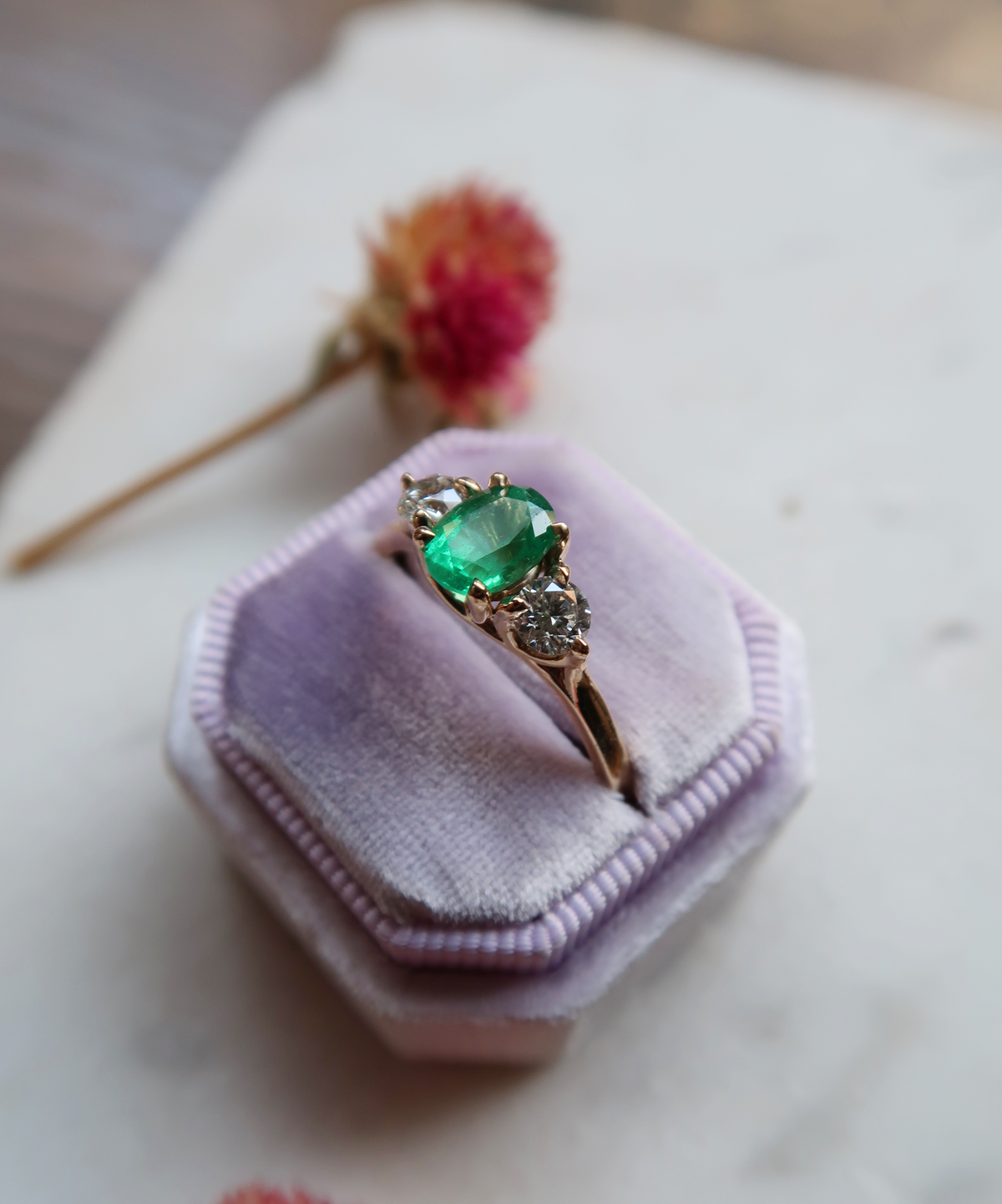 Bespoke 14k yellow gold, vintage inspired three-stone ring featuring a natural, oval cut emerald, and round brilliant cut diamond accents, held together in an intricate trellis style setting. 