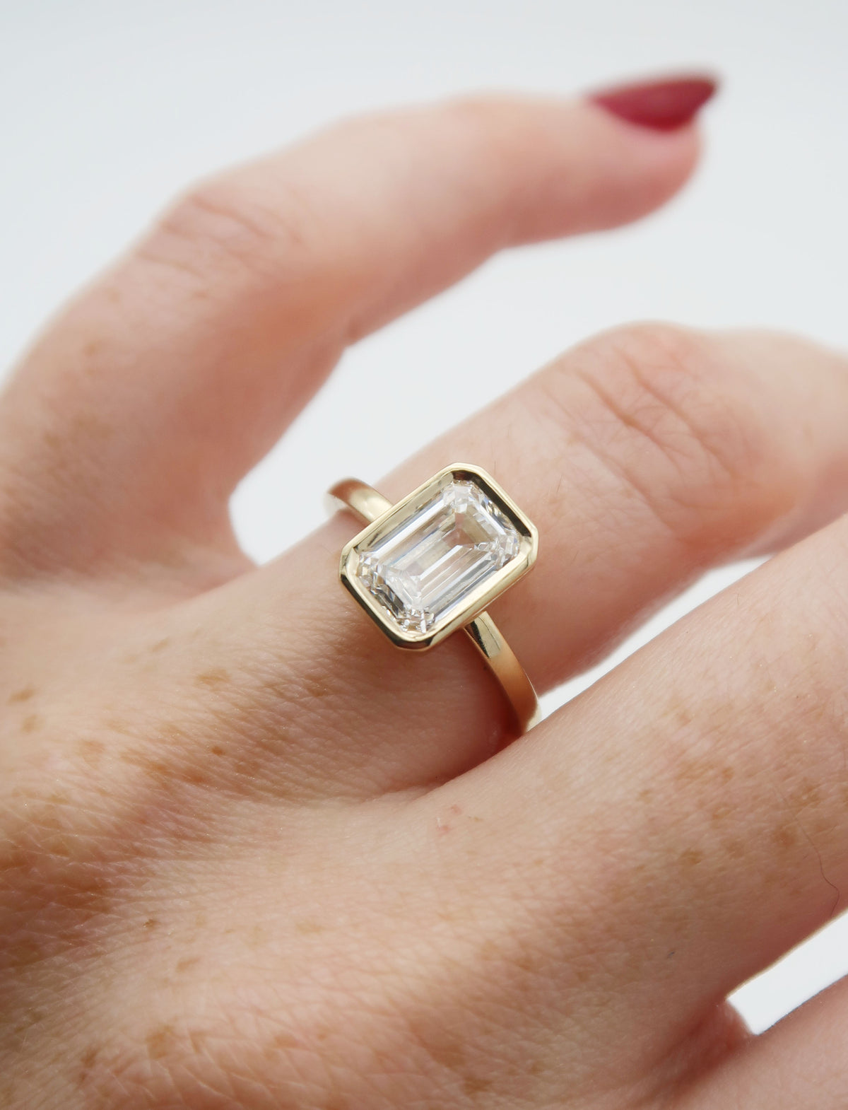 A sleek and stunning 14k yellow gold engagement ring featuring an emerald cut lab diamond, set in an elegant and timeless floating bezel. This elevated setting style makes the ring perfect for stacking!