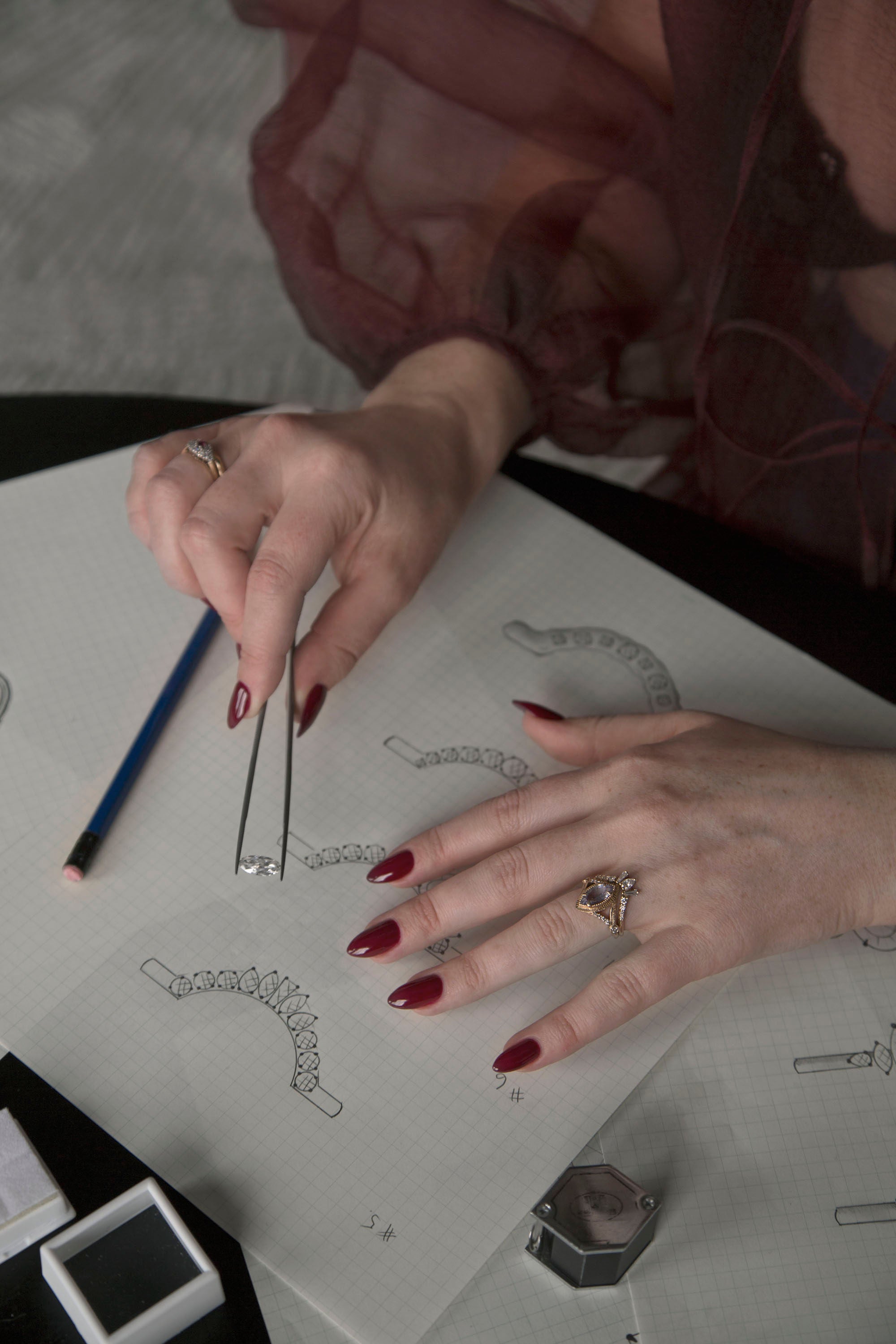 Founder of Invidiosa Jewellery using tweezers to hold a loose diamond gemstone as part of the custom design service she offers. 