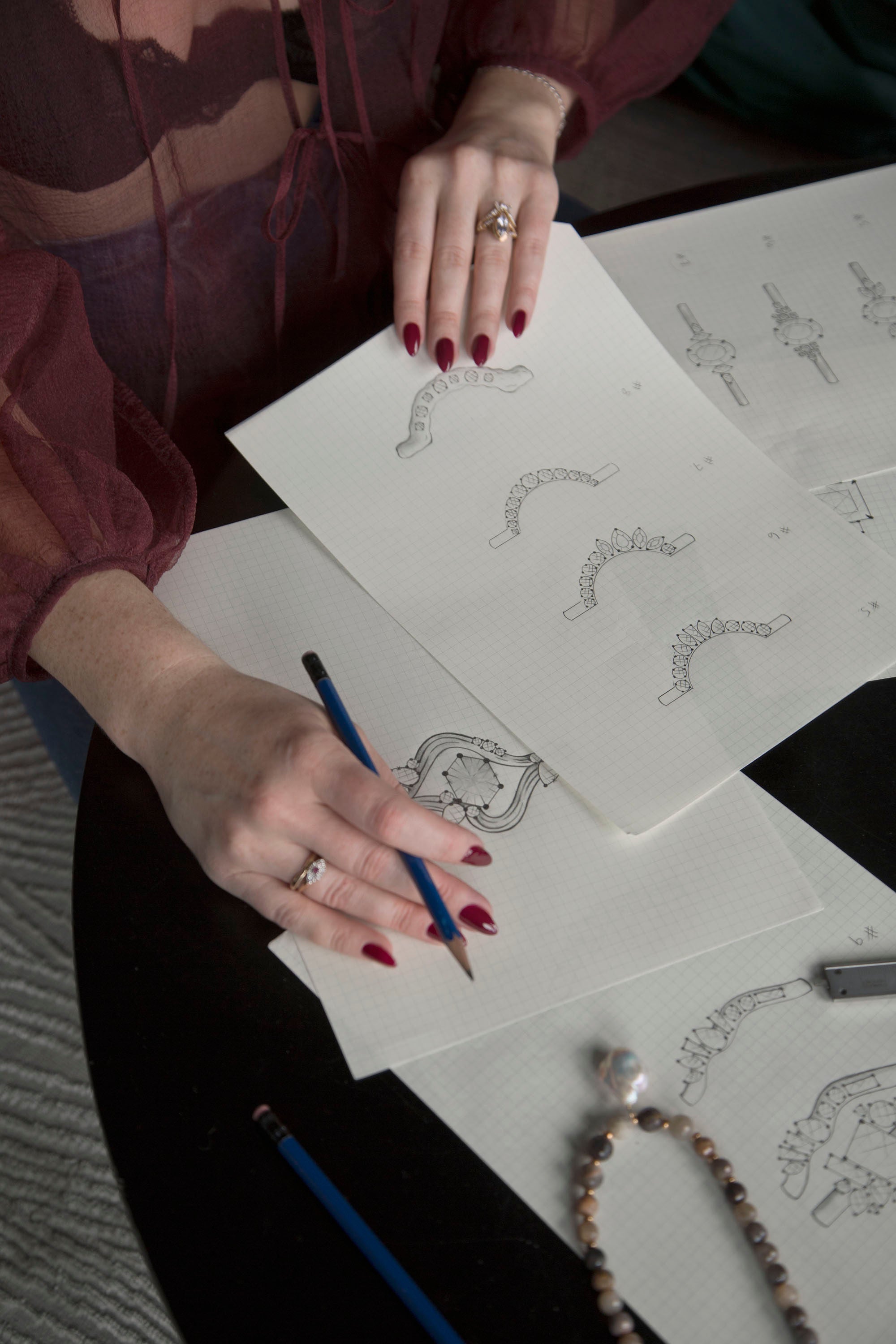 Founder of Invidiosa Jewellery, sketching custom ring designs on graph paper. 